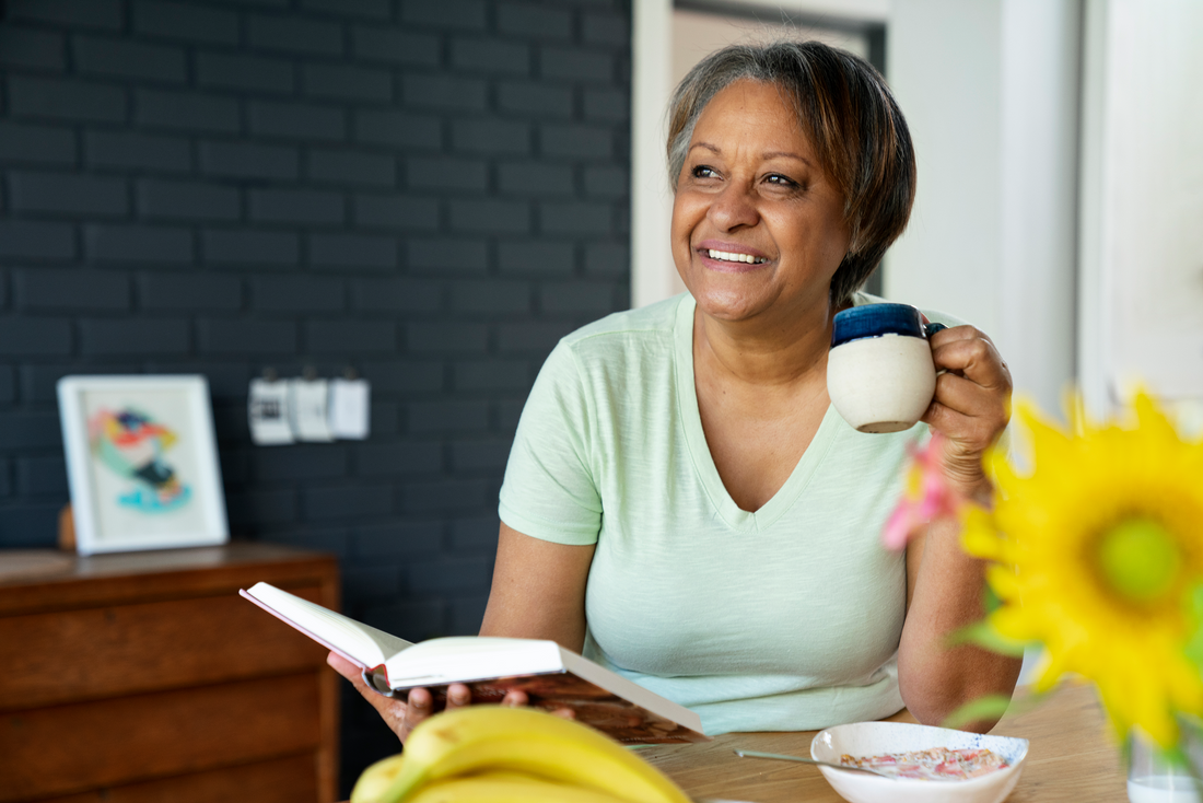 Woman smiling while reading a book with a cup of coffe in her hand