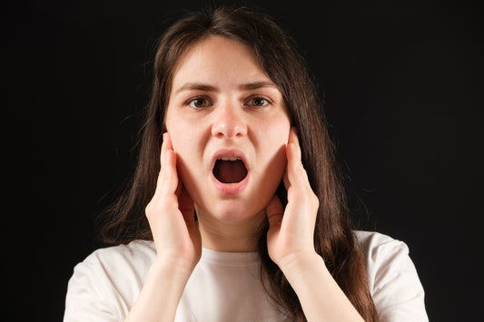 woman with hands on the sides of her face feeling her TMJ - temporomandibular joint